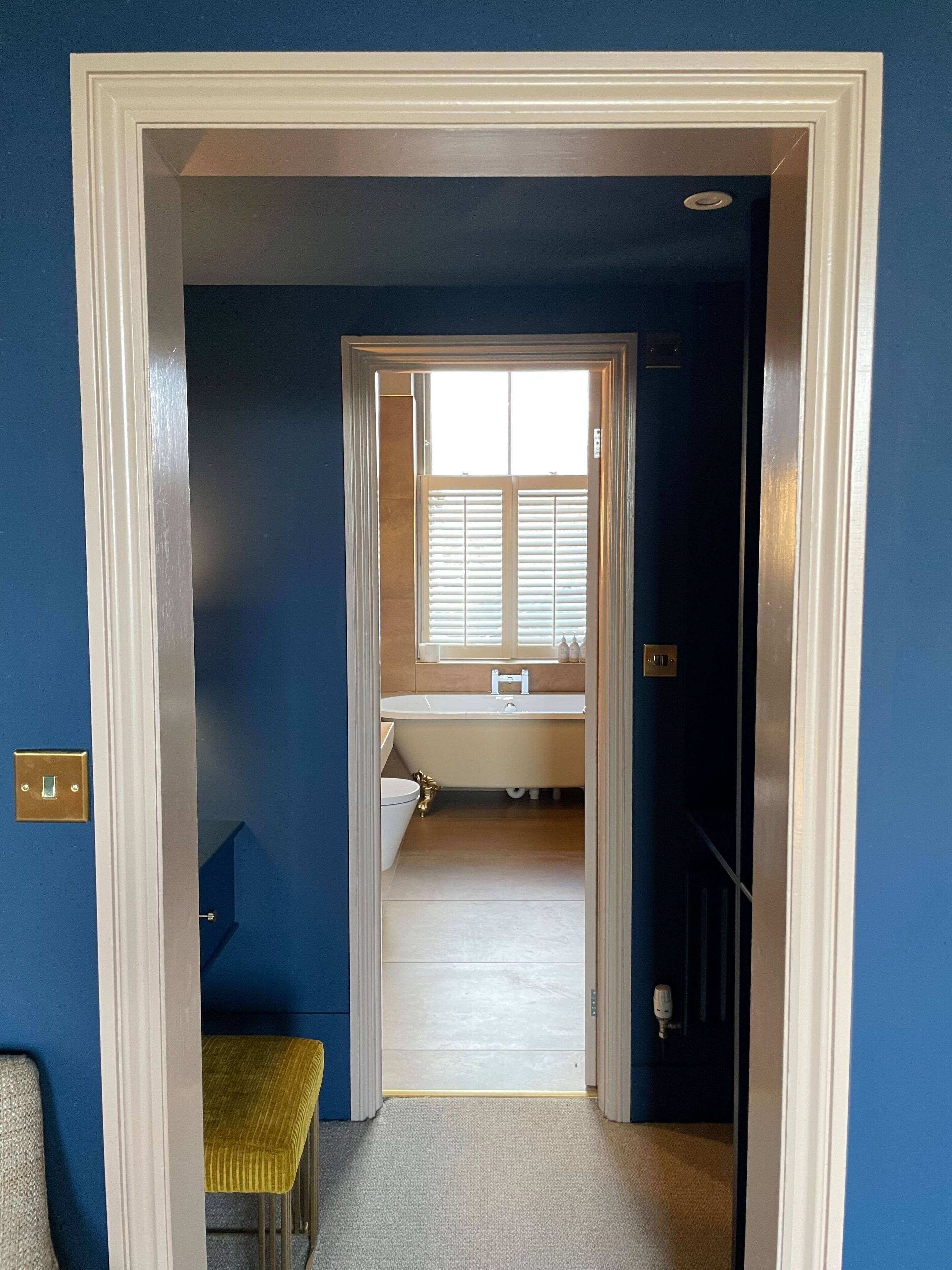 Un pasillo estrecho que conduce a un baño con ventana, inodoro y bañera.