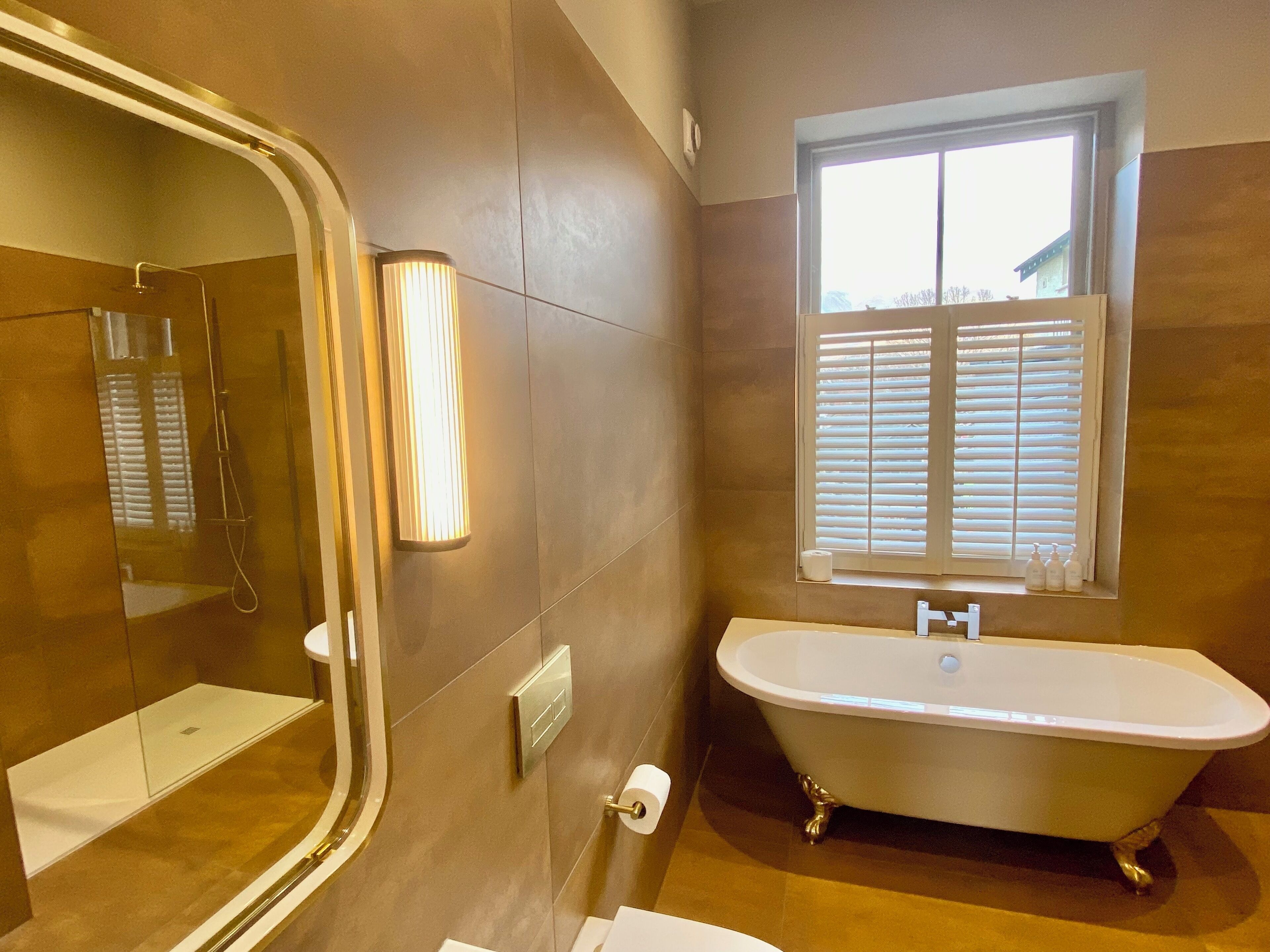 A bathroom with a bathtub, a mirror, and a window.