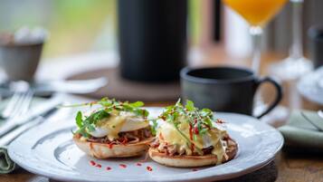 Un plato de desayuno con huevos Benedictinos y un vaso de jugo de naranja.