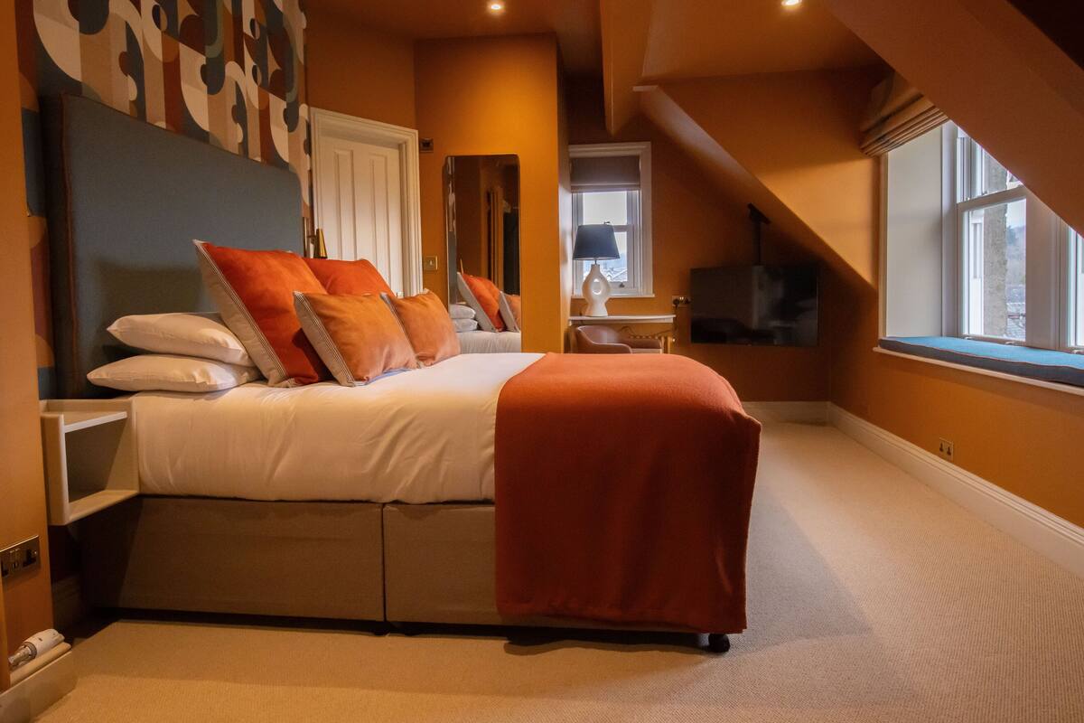 A bedroom with a large bed, a TV, and a window with a view.