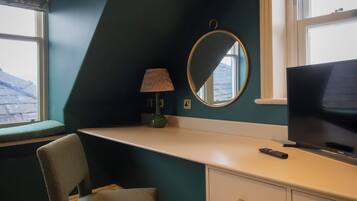 Una habitación con escritorio, silla, televisor y ventana con vista a montañas.