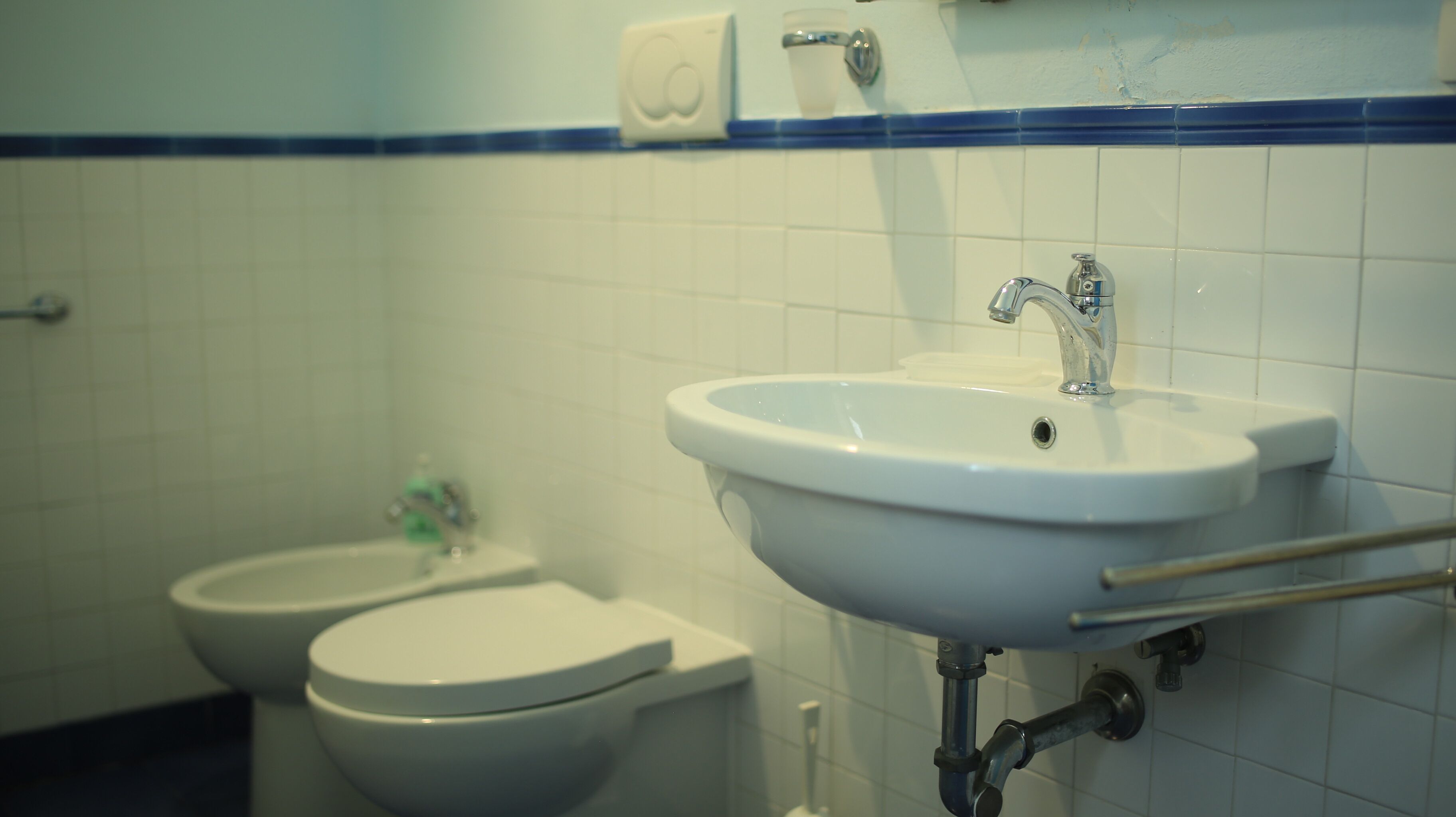Ein Badezimmer mit Waschbecken, zwei Toiletten und einem Händetrockner.