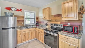 A kitchen with wooden cabinets, a stainless steel refrigerator, a microwave, and a stove. - Arkansas Fishing Getaway: Near Norfork River! (Salesville)