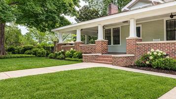 A two-story house with a covered porch, brick exterior, and a well-maintained lawn.