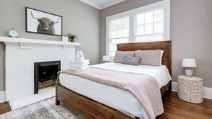A bedroom with a bed, a fireplace, a clock, and a window. - Adorable Home. Close to Everything. Great Location (Charlotte)