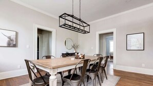A dining room with a wooden table and metal chairs, a hanging light fixture, and framed artwork on the walls. - Adorable Home. Close to Everything. Great Location (Charlotte)