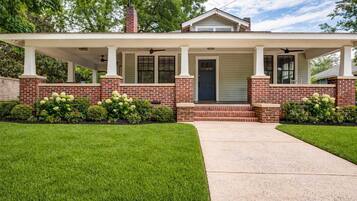 A two-story house with a covered porch, brick exterior, and a front door.