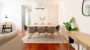 A modern dining area with a wooden table, six grey chairs, and a decorative plant. - Feel Porto Classic Apartment (Oporto)