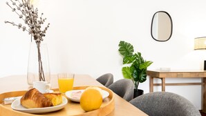 A breakfast tray with croissant, orange juice, and a lemon on a wooden table. - Feel Porto Classic Apartment (Oporto)
