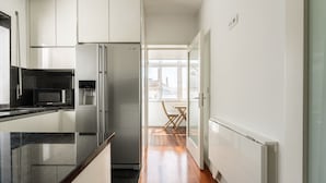 A modern kitchen with white cabinets, a stainless steel refrigerator, and a microwave. - Feel Porto Classic Apartment (Oporto)