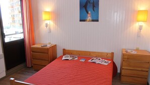 A room with a wooden bed, two bedside tables, a poster on the wall, and a window with curtains. - 50m from ski slopes, 4th floor, balcony, ski locker, 39m², Val Thorens (Val Thorens)