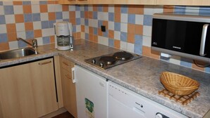 A kitchen with wooden cabinets, a microwave, a coffee maker, and a dishwasher. - 50m from ski slopes, 4th floor, balcony, ski locker, 39m², Val Thorens (Val Thorens)