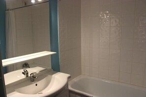 A bathroom with a white sink, mirror, and bathtub.