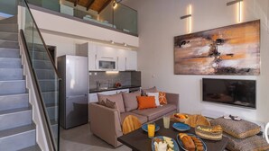 A modern kitchen with white cabinets, a stainless steel refrigerator, and a dining area with a table set for a meal. - OceanEye Suites - Fortuna (Panormo)