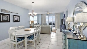 A dining area with a white table and chairs, a chandelier, and a ceiling fan.