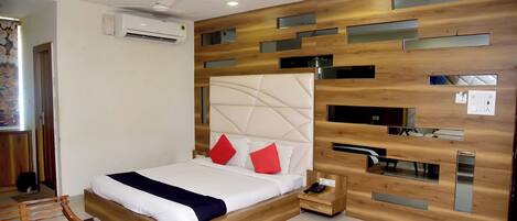 A modern bedroom with a wooden headboard, a bed with white bedding and red pillows, a bedside table with a phone, and a ceiling fan.
