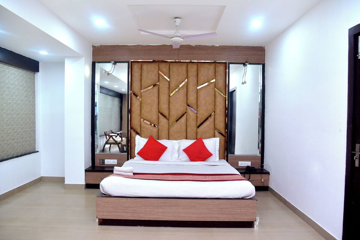 A modern bedroom with a large bed, a ceiling fan, and a mirror above the bed.