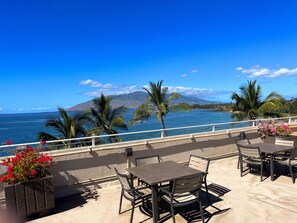 Enjoy ocean views from this outdoor space with tables, chairs, and potted plants.