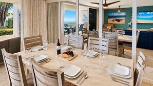 A dining area with a large table set for six, surrounded by wooden chairs. - Exceptional Oceanview at Royal Mauian | Rare 3 Bedroom and Oceanfront Living (Kihei)