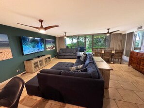 Relax in this spacious living room with a large sectional sofa, flat-screen TV, and dining area.