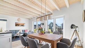 Una cocina moderna con una mesa y sillas de madera, un comedor con vista al jardín trasero y un ventanal grande.