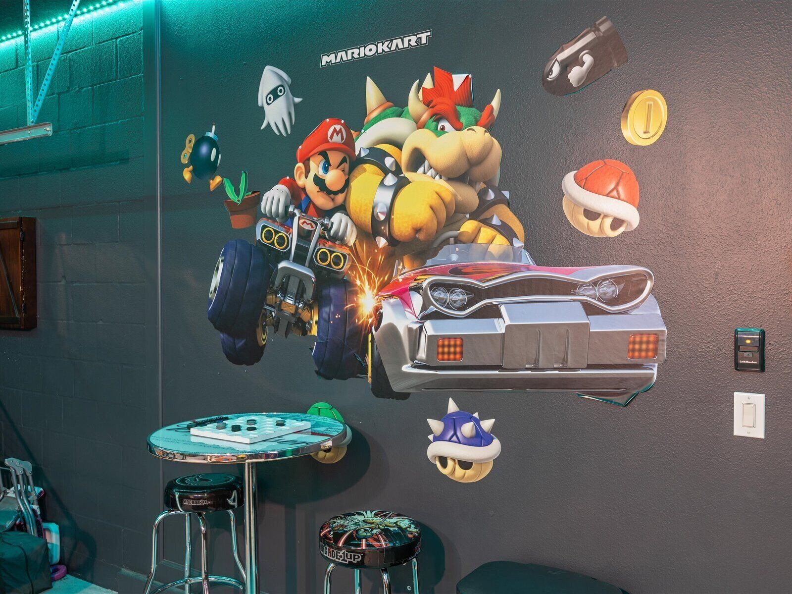 A wall with a Mario Kart mural, a small table, and a stool.