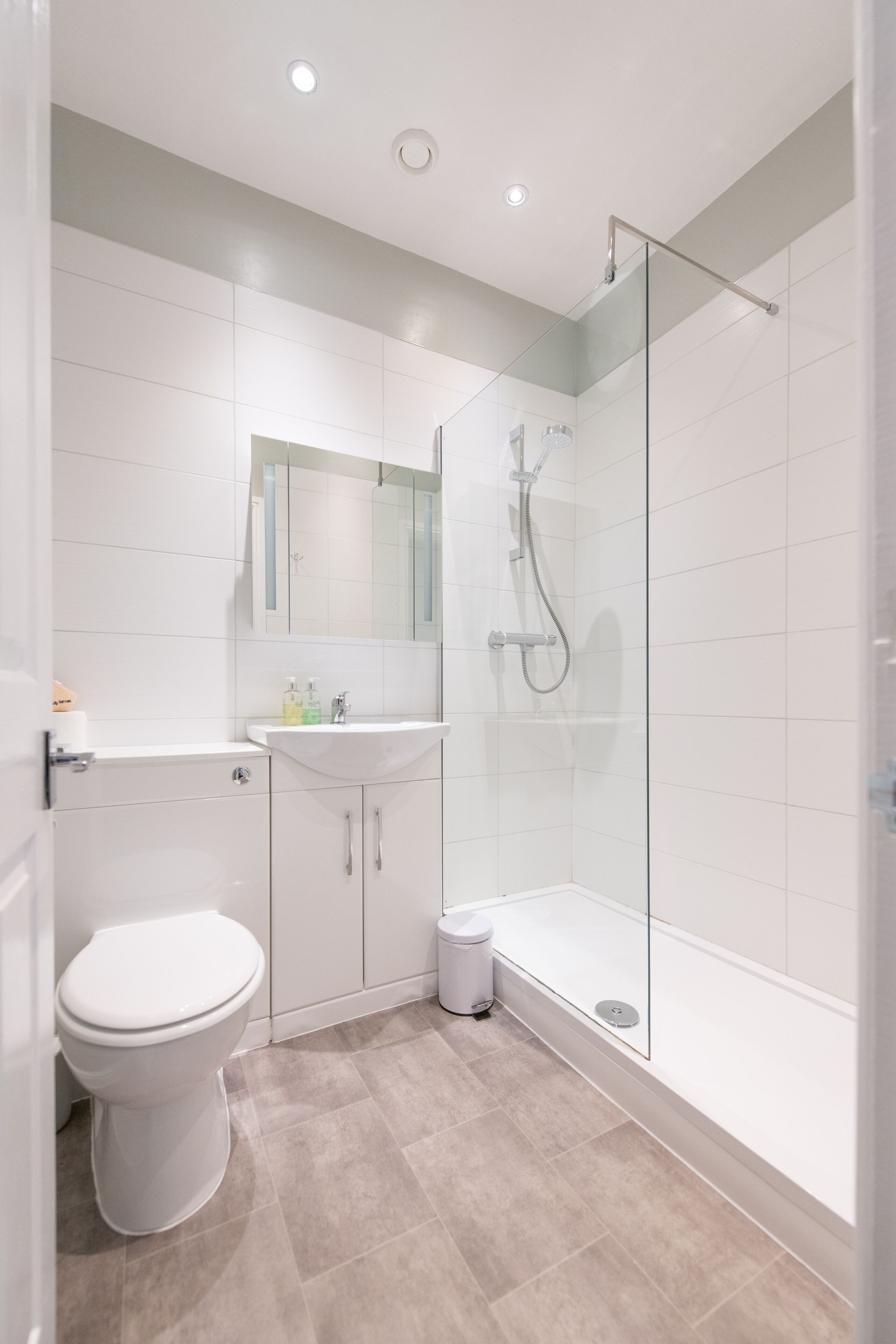 Une salle de bain moderne équipée de toilettes, d’un lavabo et d’une douche à parois de verre.