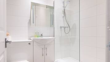 Un baño moderno con inodoro, lavamanos y ducha con mampara de vidrio.