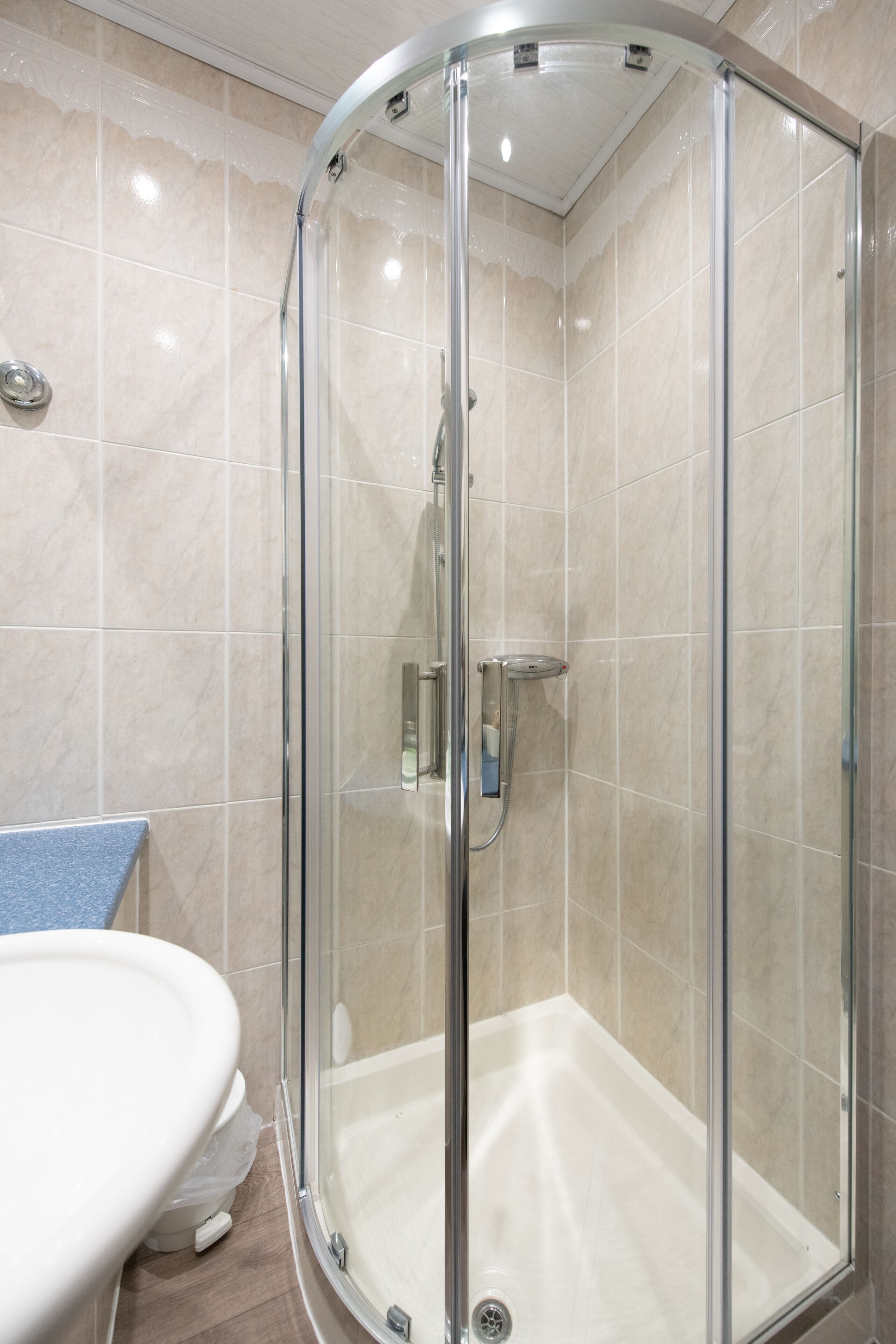 A modern bathroom with a glass-enclosed shower, a white toilet, and a blue towel rack.