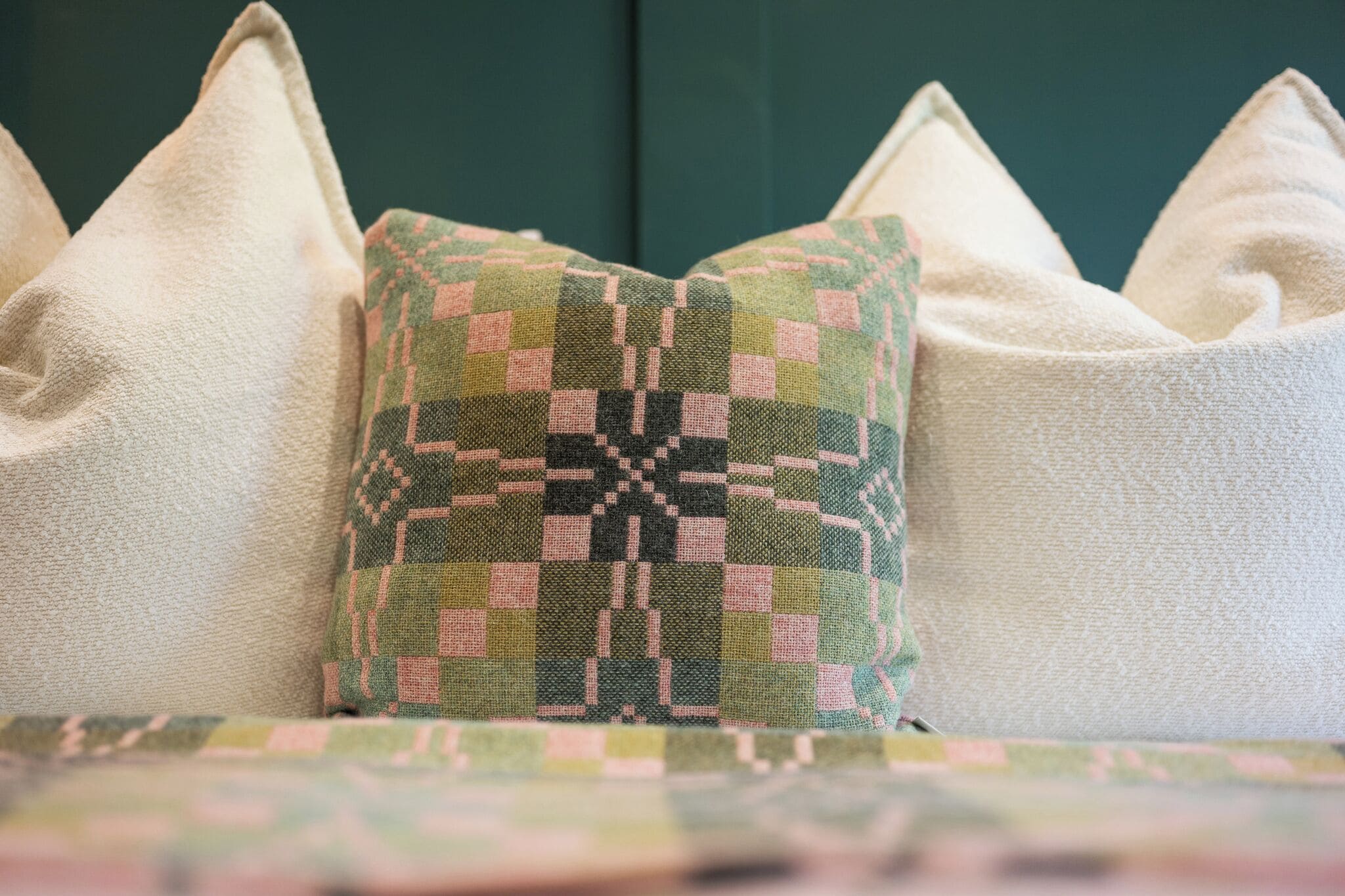 A bed with a patterned pillow and two plain pillows.