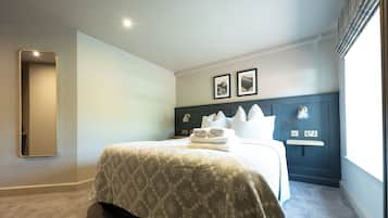Una habitación de hotel con cama, mesita de noche, espejo y dos cuadros en la pared.