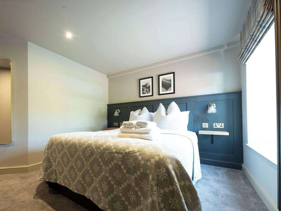 Una habitación de hotel con cama, mesita de noche, espejo y dos cuadros en la pared.