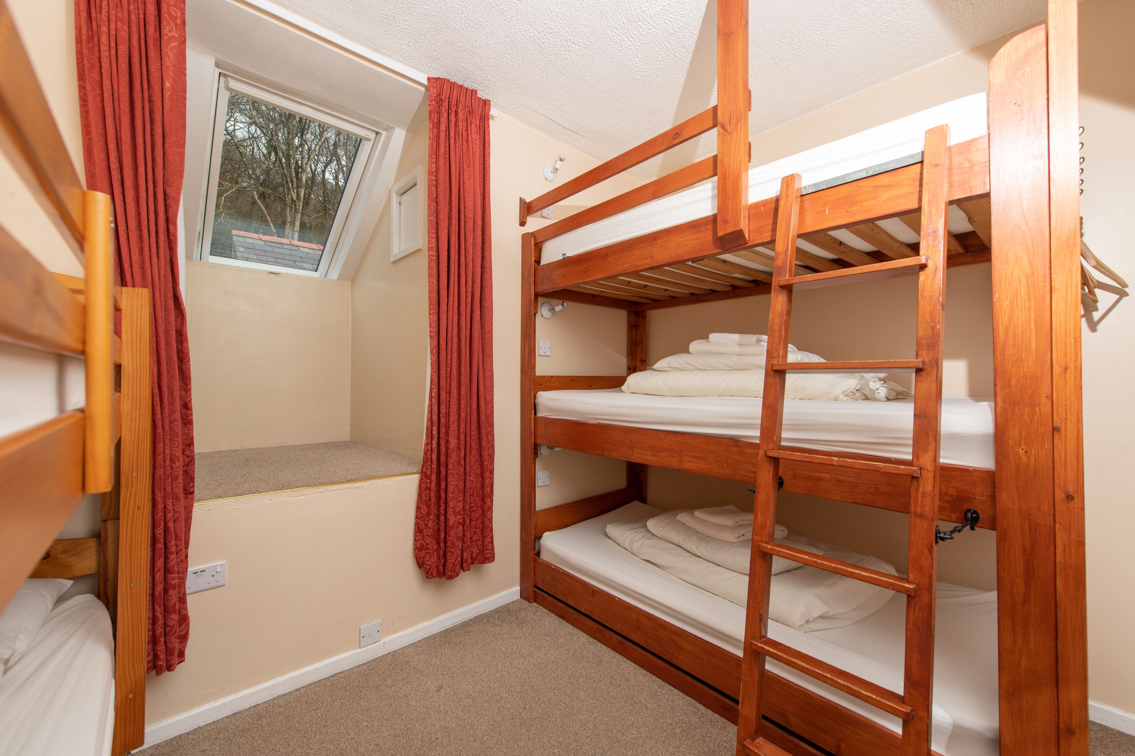 A bunk bed room with a window and red curtains.