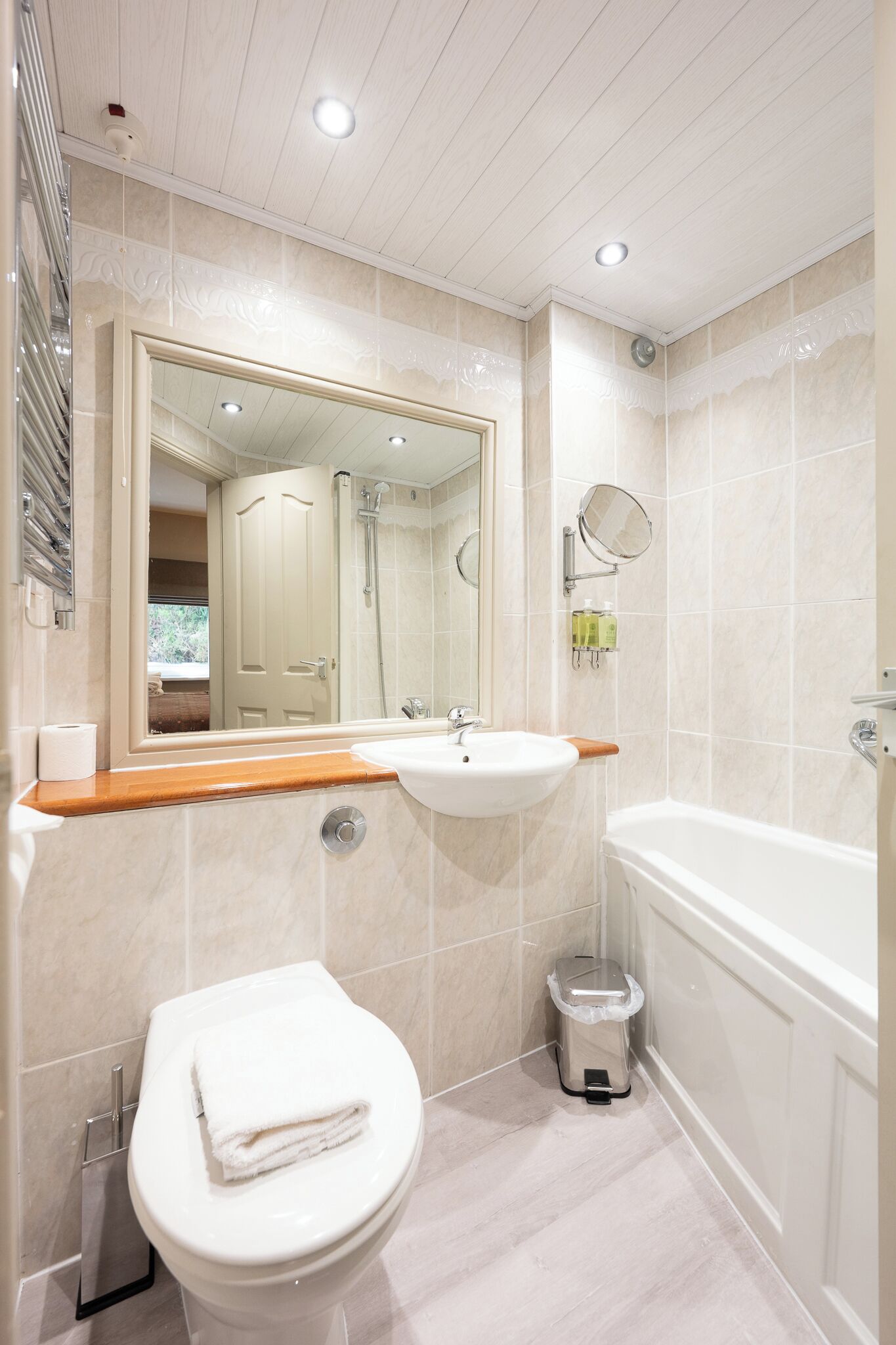 Un baño moderno con inodoro, lavabo, espejo y bañera.