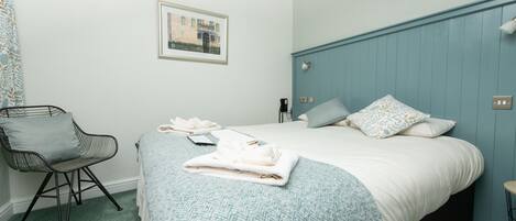 A neatly arranged bedroom with a bed, a chair, and a bedside table.