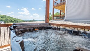 A hot tub on a wooden deck with a view of a house and a forested area. - Hot Tub, Lake Views, Mins to SDC, Pools-Sleeps 16 (Branson)