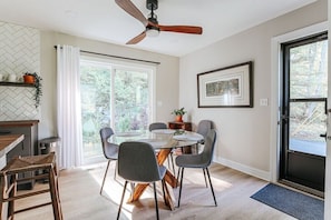 Une cuisine moderne avec un pare-feu en motif chevron, un coin repas avec une table ronde et quatre chaises, et un ventilateur de plafond.