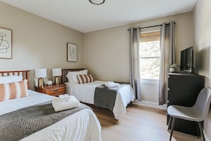 Une chambre d’hôtel avec deux lits, un bureau, une chaise et un téléviseur.