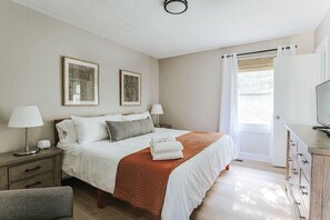 Une chambre à coucher avec un lit, deux lampes de chevet, une commode, une chaise et deux tableaux encadrés accrochés au mur.