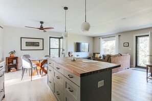 A modern kitchen with a wooden island, white chairs, and a dining table. - Hillside Haven: Modern Retreat, Mountain Views (Faber)