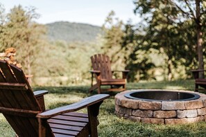 A wooden deck with Adirondack chairs and a stone fire pit. - Hillside Haven: Modern Retreat, Mountain Views (Faber)