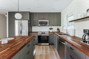 Una cocina moderna con armarios grises, electrodomésticos de acero inoxidable y encimeras de madera.