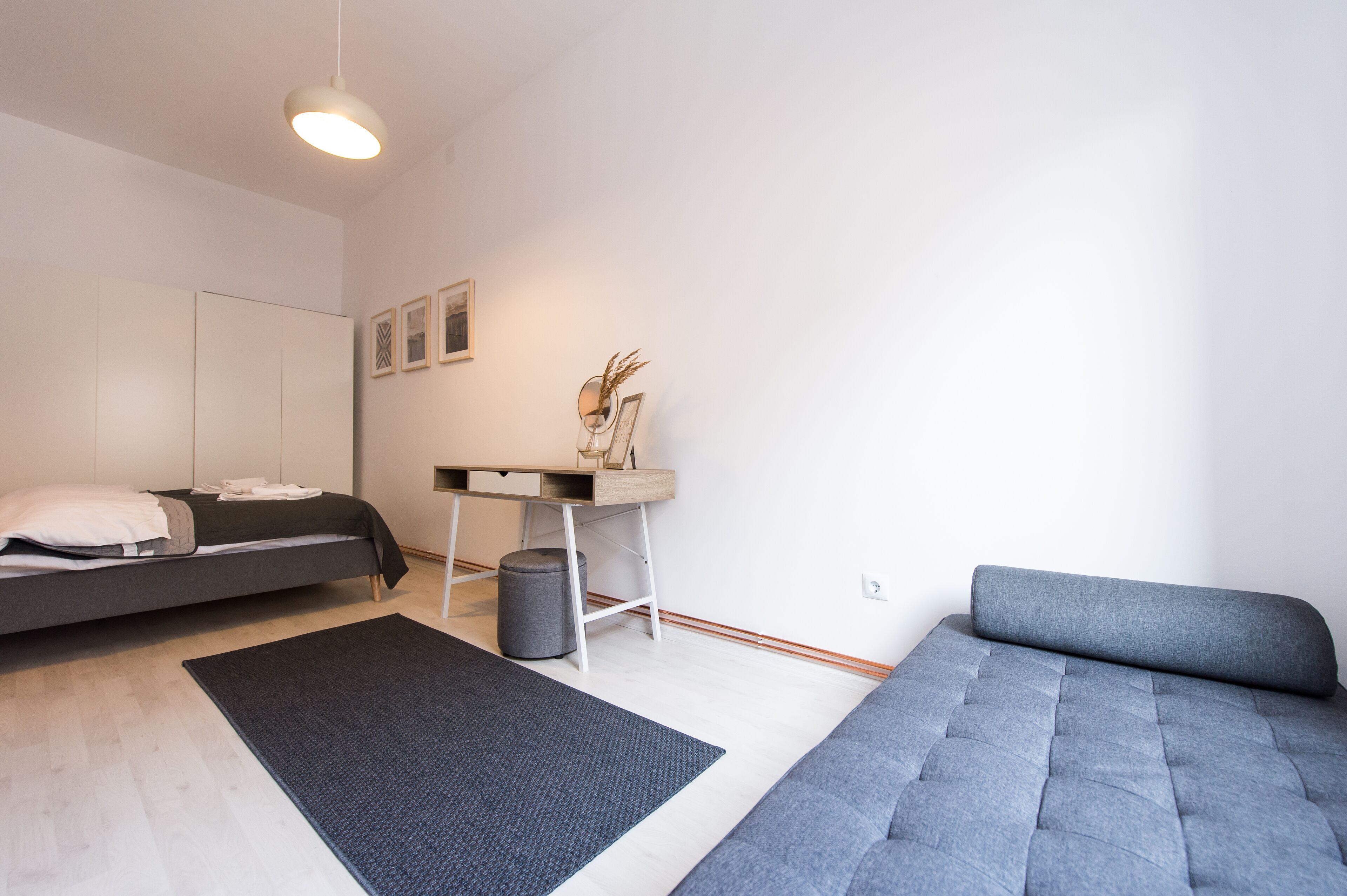 Een moderne slaapkamer met een bed, een bureau en een bank.