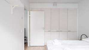 A minimalist bedroom with a large wardrobe, a neatly made bed, and a small bedside table. - 1BR & Balcony next to Railway Station (Tampere)