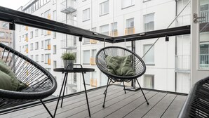 A balcony with two black wicker chairs, one with a green cushion, and a small table with a potted plant. - 1BR & Balcony next to Railway Station (Tampere)