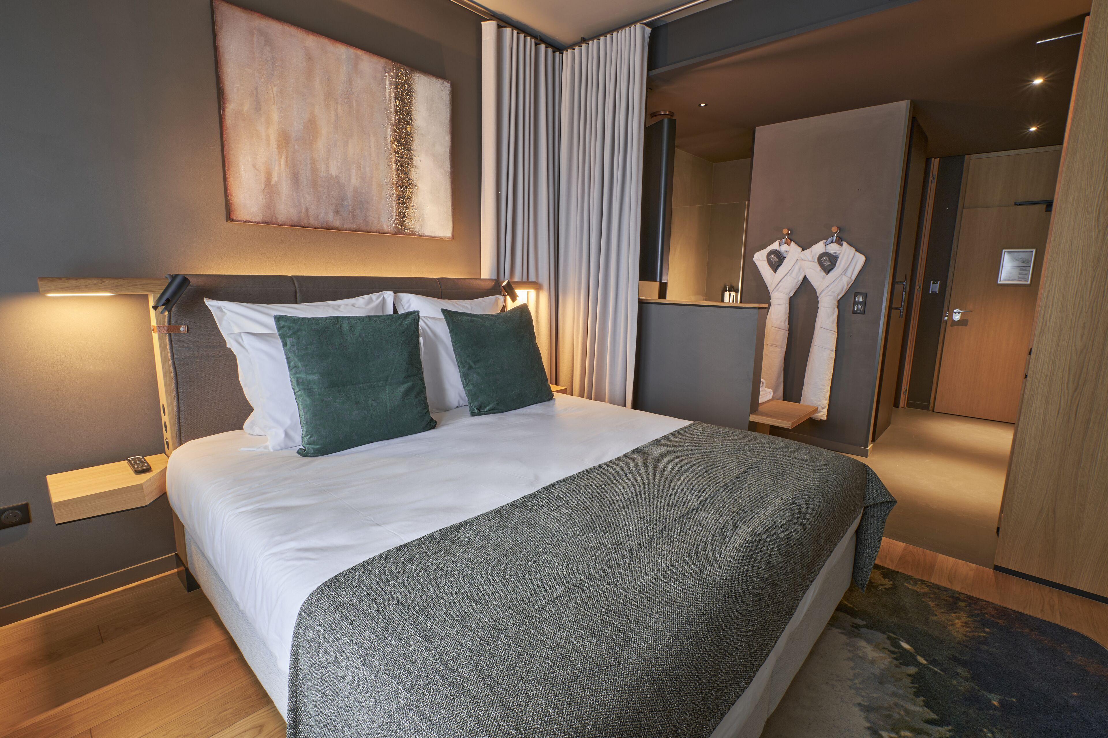 Una camera d'albergo moderna con un letto grande, un comodino e uno specchio.