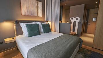 Una camera d'albergo moderna con un letto grande, un comodino e uno specchio.