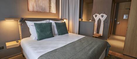 Una habitación de hotel moderna con una cama grande, una mesita de noche y un espejo.