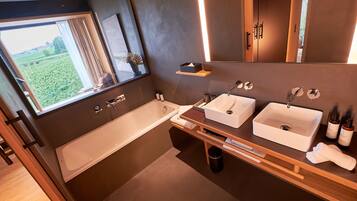 A modern bathroom with a large window, a bathtub, two sinks, and wooden shelves.