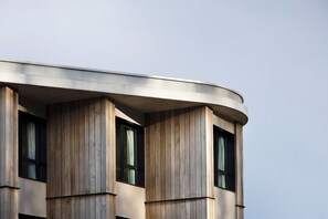 Ein Gebäude mit einer geschwungenen Fassade, großen Fenstern und vertikalen Holzpaneelen.